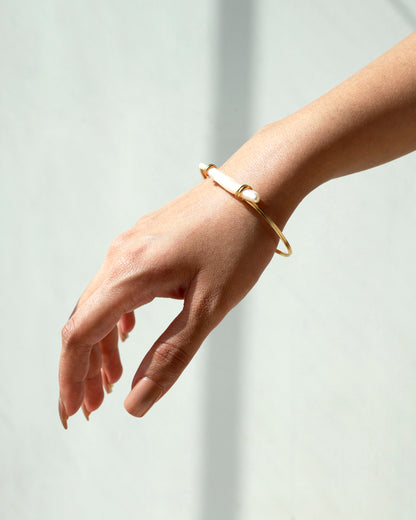 Gold bracelet on a person's wrist against a light background